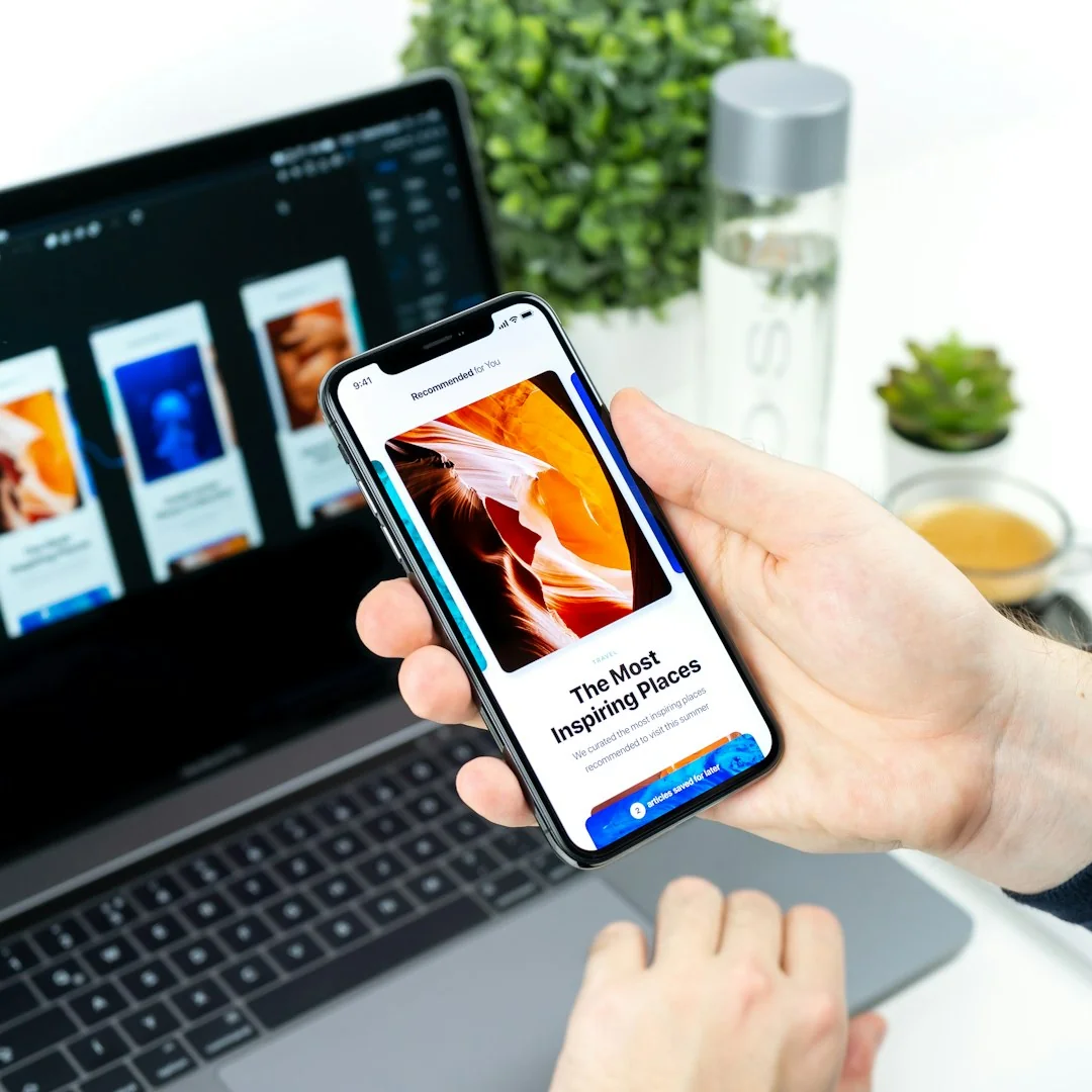 Gros plan d’un smartphone affichant une image floutée, posé sur un bureau à côté d’un ordinateur portable.
